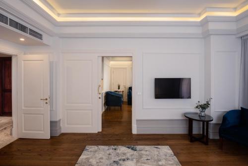 a living room with white walls and a tv on a wall at Maran Residence in Cairo