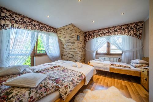 a bedroom with two beds and two windows at Podhalański Domek 2 in Biały Dunajec