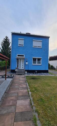 une maison bleue avec une porte blanche dans l'établissement Ferienwohnung am Grambker See, à Brême