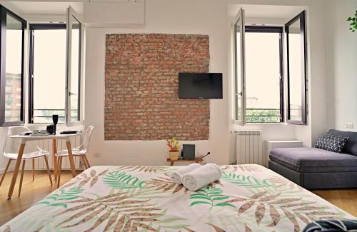 een slaapkamer met een bed en een bakstenen muur bij P&D Apartments Darsena in Milaan