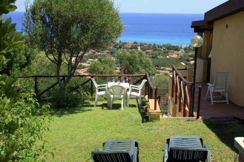 a patio with a table and chairs and the ocean at Villetta Mare e Sole - vista mare, giardino privato, vicino spiaggia in Costa Rei