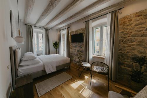 a bedroom with a bed and a chair and windows at Porto Nativo Split in Split