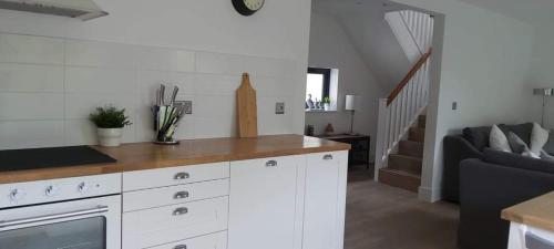 a kitchen with white cabinets and a couch and stairs at Newquay Rialton Holiday Home in Newquay