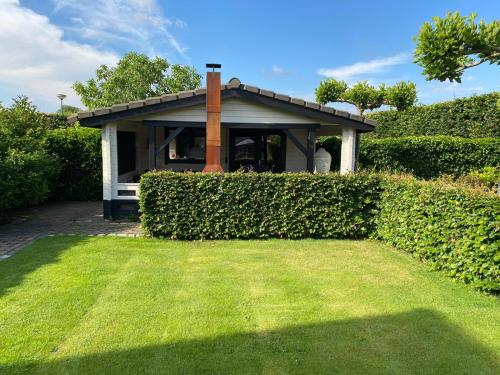 a house with a hedge in front of a yard at Hof van donzel in Nistelrode