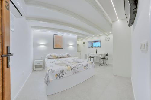 Apartment light in Pula في بولا: غرفة بيضاء مع سرير وطاولة