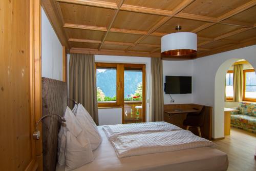 een slaapkamer met een bed, een bureau en een televisie bij Haus am Sonnenhang in Finkenberg