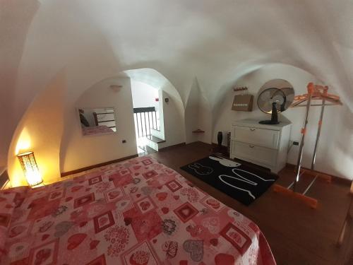 a bedroom with a bed with a red bedspread and a table at Casetta Miracoli Salento in Tuglie