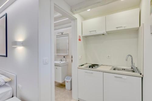 a kitchen with white cabinets and a sink at Apartment light in Pula in Pula