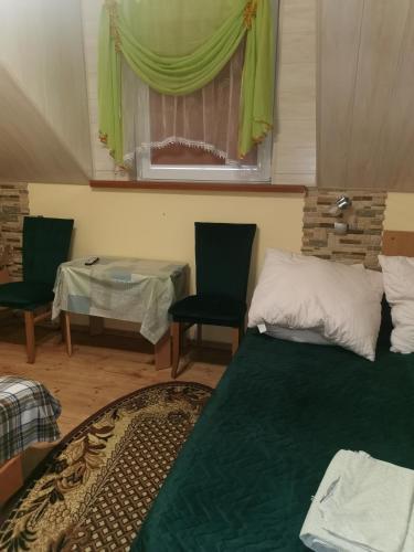 a room with a bed and two chairs and a window at Czerwonki Apartament in Mrągowo