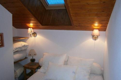 a bedroom with a bed with white pillows and a wooden ceiling at Appartement duplex 7 pers 3 chambres pied des pistes La Joue du Loup in Le Dévoluy