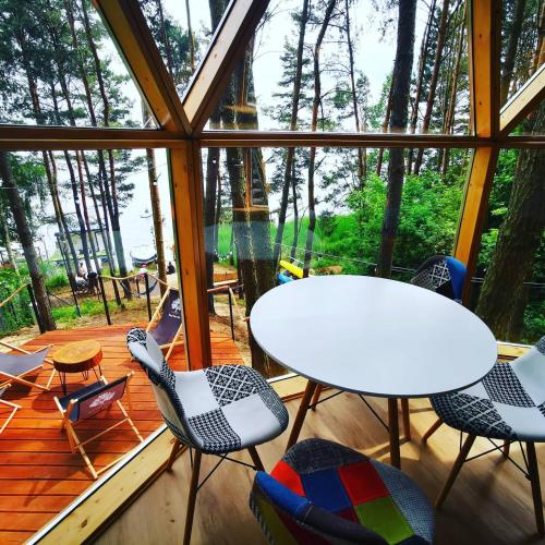 a room with a table and chairs on a deck at Nad Narvią - Glamp in Serock