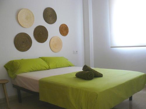 ein Schlafzimmer mit einem Bett mit grüner Bettwäsche und Platten an der Wand in der Unterkunft PISO CENTRICO EN BENICARLO 2 in Benicarló