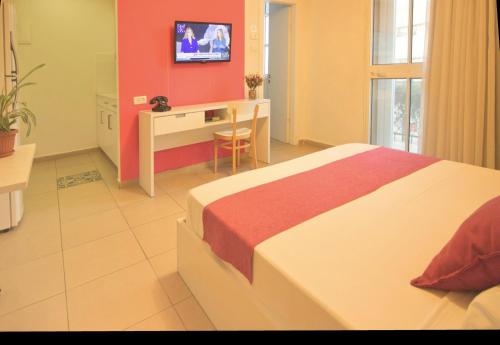 a bedroom with a bed and a desk and a tv at 1926 Designed ApartHotel in Haifa