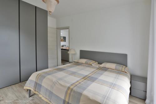 a white bedroom with a bed with a striped blanket at Appartamenti Ramarro in Ronco s/Ascona - Porto Ronco