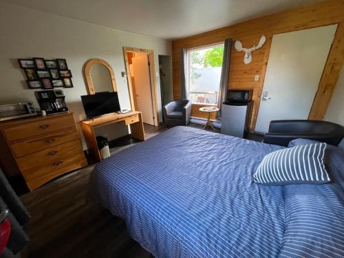 a bedroom with a bed and a desk with a computer at Auberge et Chalets sur le Lac in Lac-Mégantic