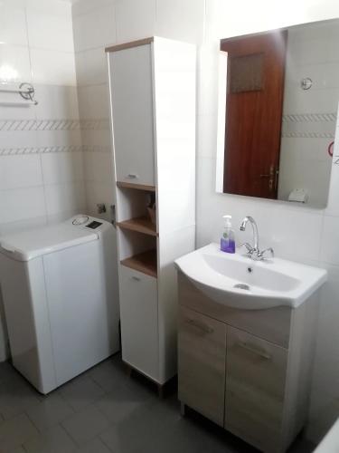 a white bathroom with a sink and a mirror at Petrochori Memories House- Floor 1 in Petrochori