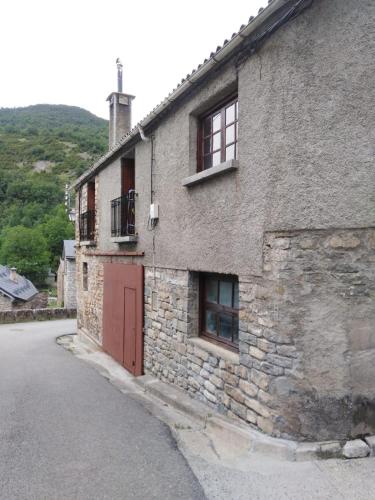 a stone building with a red door on a street at Casa Rural O´LIENO in Oto