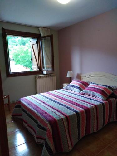 a bedroom with a bed with a striped blanket on it at Casa Rural O´LIENO in Oto