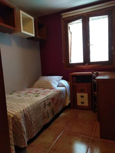 a small bedroom with a bed and a window at Casa Rural O´LIENO in Oto
