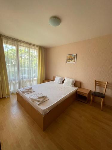 a bedroom with a large bed and a chair at Apartments in Panorama Beach Vigo Nessebar in Nesebar