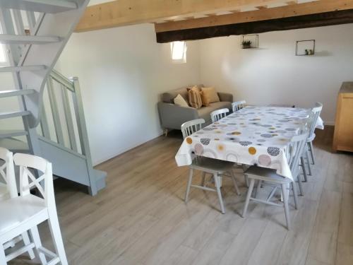 a dining room with a table and a couch at Gîte Les Mirabelles Calme et Reposant in Vieux-Pont-En-Auge