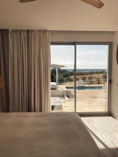 una camera da letto con una grande finestra con vista sulla piscina di Casa Branca - Monte dos Rolas ad Alcácer do Sal