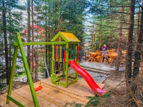 a playground with a slide in the woods at Altitude Guest House Ranca in Ranca