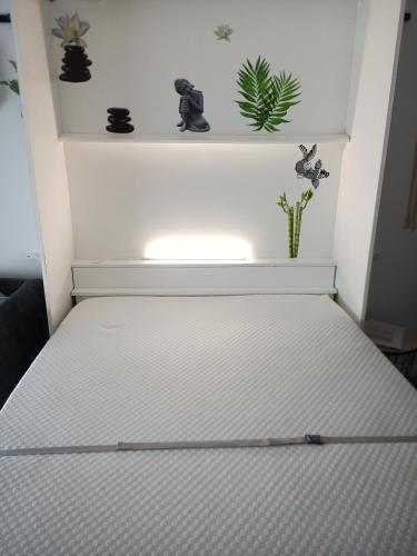 - un lit blanc dans une chambre avec des plantes sur une étagère dans l'établissement cosy STUDIO 4 personnes, proche mer et commerce 0 chambre, au Grau-du-Roi