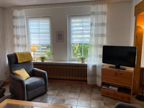 a living room with a tv and a chair and a window at Ferienwohnung Ram 1 in Hermannsburg