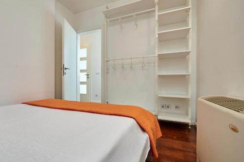 a white bedroom with an orange blanket on a bed at Apartments Gea Trogir in Trogir
