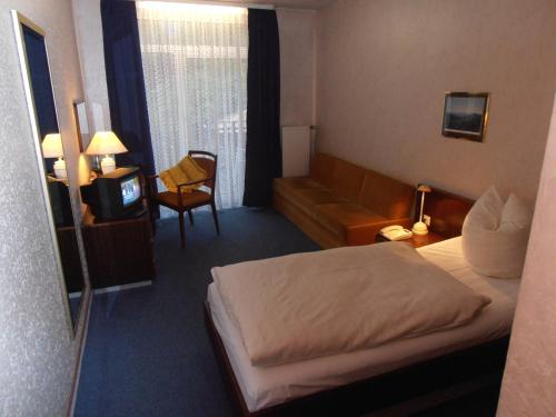 a hotel room with a bed and a couch and a television at Hotel am Deister in Barsinghausen