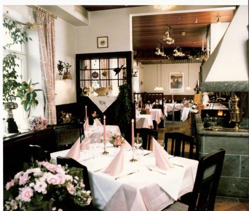 ein Esszimmer mit Tischen, rosa Servietten und Blumen in der Unterkunft Hotel am Deister in Barsinghausen