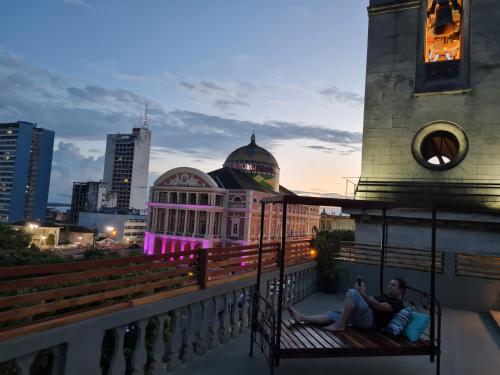 dos personas sentadas en un banco en un balcón en Hotel Casa Dos Frades, en Manaus