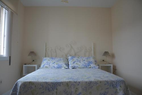 Dormitorio blanco con cama con sábanas y almohadas azules en Apartamento Sira en Sanxenxo