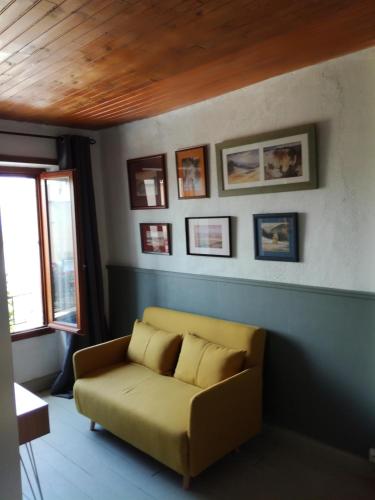a living room with a yellow couch and pictures on the wall at Gîte les 4 Vents in Pradelles