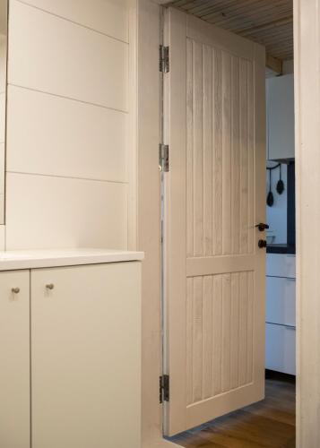 a kitchen with white cabinets and a door at Alyvų Namai Nida in Nida