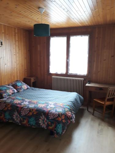 a bedroom with a bed and a desk and two windows at Les Granges in La Clusaz