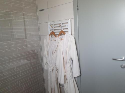 a white robe hanging on a rack in a bathroom at Apartmani Fenestra -Zagorka in Otočac
