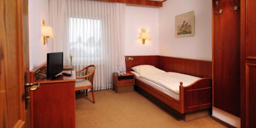 a bedroom with a bed and a desk with a television at Hotel Alte Post Garni in Ginsheim-Gustavsburg