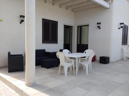 un patio con mesa, sillas y sofá en Casa vacanze vista mare Salento Tricase Porto villa Antonio e villa Rosanna, en Marina Porto