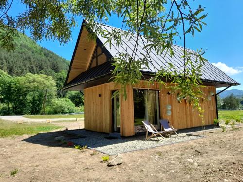 a small wooden cabin with two chairs in front of it at Mała Gorczańska Chatka in Ochotnica Dolna