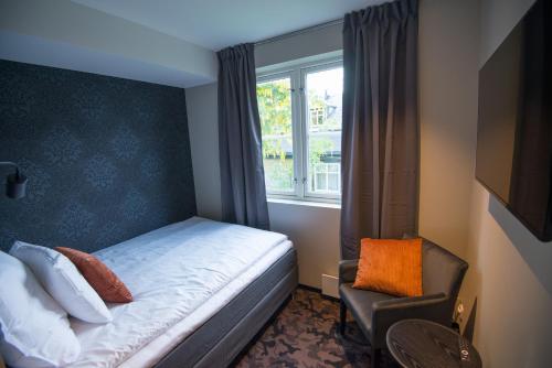 a bedroom with a bed and a window and a chair at Sandnessjøen Overnatting in Sandnessjøen
