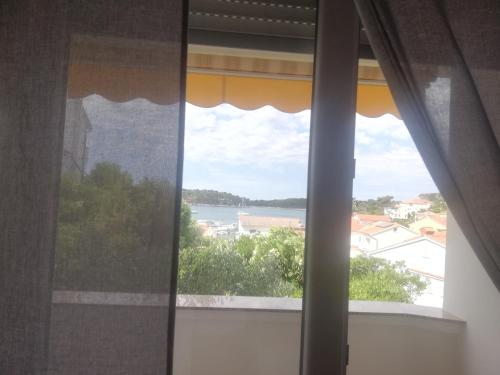 a window with a view of the water at Riviera Rooms and Apartments in Rab