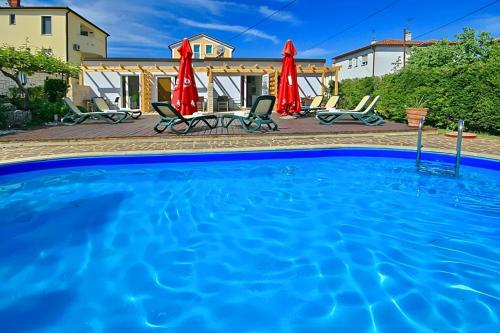 a large swimming pool with chairs and umbrellas at Apartmani Elio in Umag