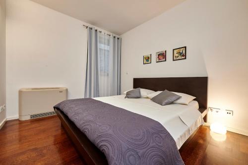 a bedroom with a large bed with a purple blanket at Apartments Gea Trogir in Trogir