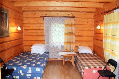 Habitación con 2 camas y ventana en una cabaña de madera. en Kempings Sīļi, en Jūrkalne