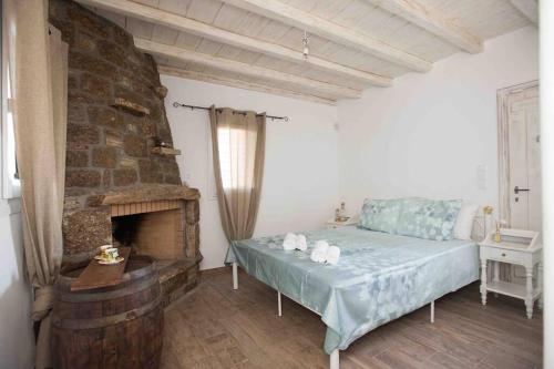 a bedroom with a bed and a stone fireplace at Villa Jakie in Mýkonos City