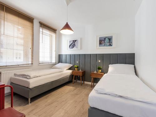 1 dormitorio con 2 camas, mesa y ventanas en VacationClub – Dubois 16C Apartament 11 en Kołobrzeg