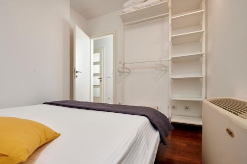 a white bedroom with a bed and shelves at Apartments Gea Trogir in Trogir
