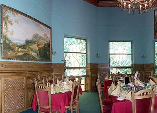 a dining room with tables and chairs and a painting at Morshynska Vezha Hotel in Morshin